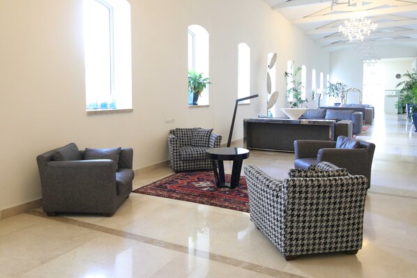 A spacious lobby with a grey sofa, a houndstooth armchair, and a small round table.