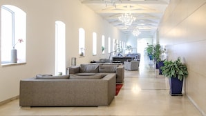 Ein geräumiger Flur mit einem modernen Sofa, Zimmerpflanzen und einem Fernseher im Hintergrund.