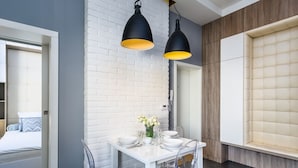 A modern dining area with a white table set for four, clear chairs, and two black pendant lights with yellow shades. - Elite Apartments Sopot Zacisze (Gdansk)