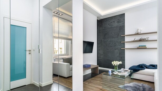 A modern living room with a glass partition, a white sofa, a coffee table, and a dark accent wall. - Elite Apartments Sopot Zacisze (Gdansk)