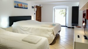 Une chambre d’hôtel avec deux lits, un tableau au mur, une porte et un téléviseur posé sur un meuble.