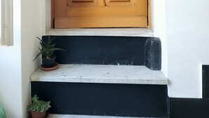 Une porte en bois sur laquelle est inscrit le chiffre « 2 », un pot de fleurs placé à gauche et une marche en marbre menant à la porte.