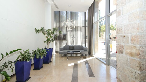 A modern lobby with a seating area, large windows, and potted plants.
