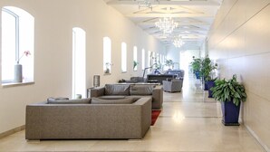 A spacious hallway with a modern sofa, potted plants, and a television in the background.