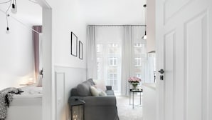 A modern living room with a grey sofa, a small side table with a vase, and a black lantern on the floor.