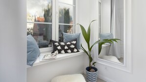 A room with a large window, a potted plant, and a white fluffy rug.