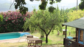 A wooden deck with a table and chairs, a small pool, and a wooden cabin with a blue roof. - Casa del Paso (Bolulla)
