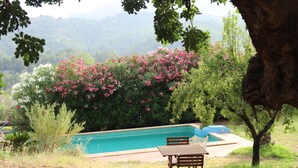 A swimming pool with a wooden table and chairs in a garden setting. - Casa del Paso (Bolulla)