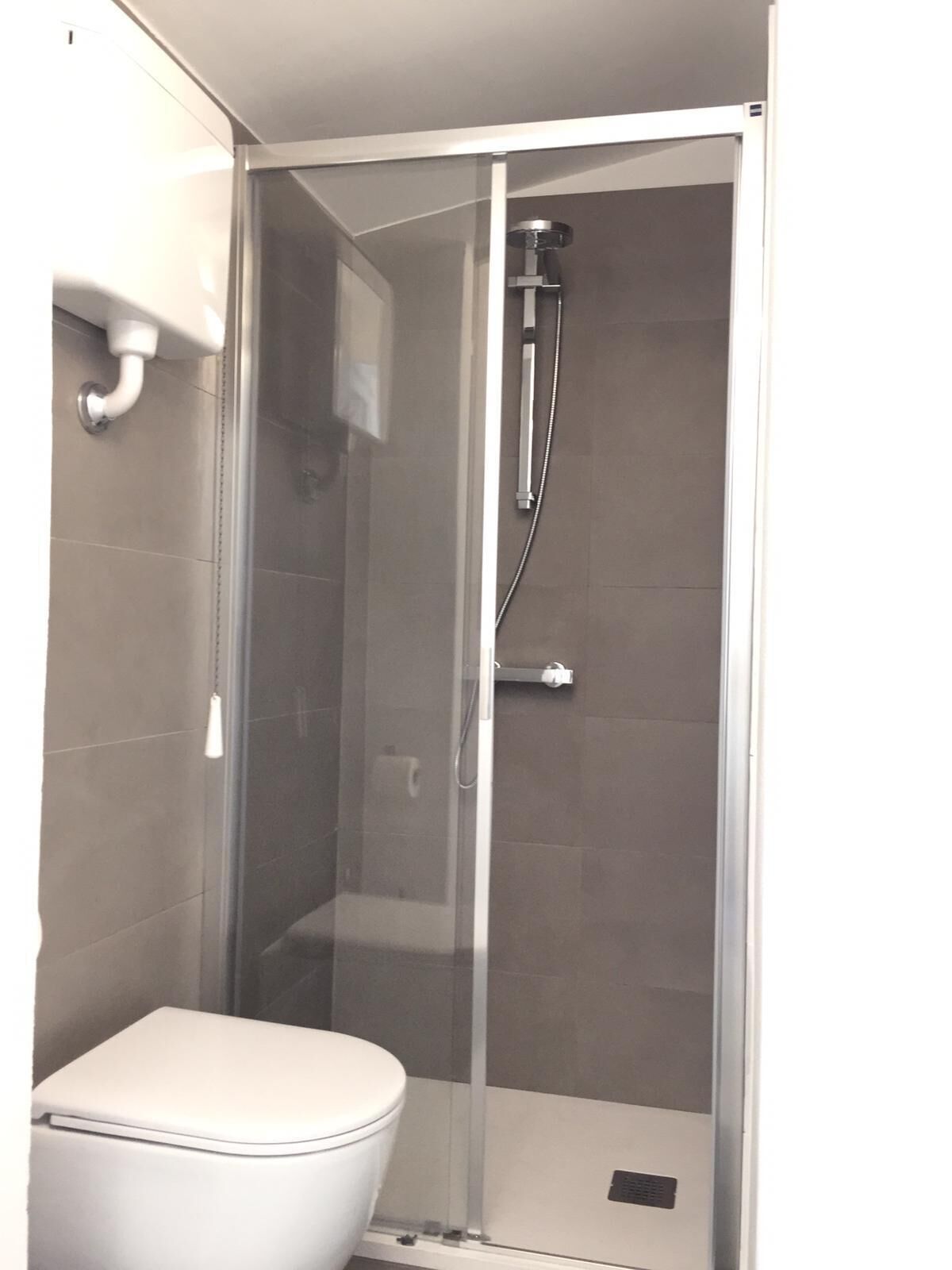 Une salle de bain comprenant des toilettes, un espace douche et une porte en verre.