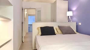 A bedroom with a bed, a nightstand, a lamp, and a mirror. - Happy Holiday Sanremo (Sanremo)