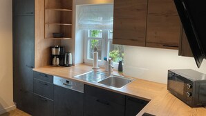 Een moderne keuken met donkere kasten, een roestvrijstalen spoelbak en een ingebouwde magnetron.