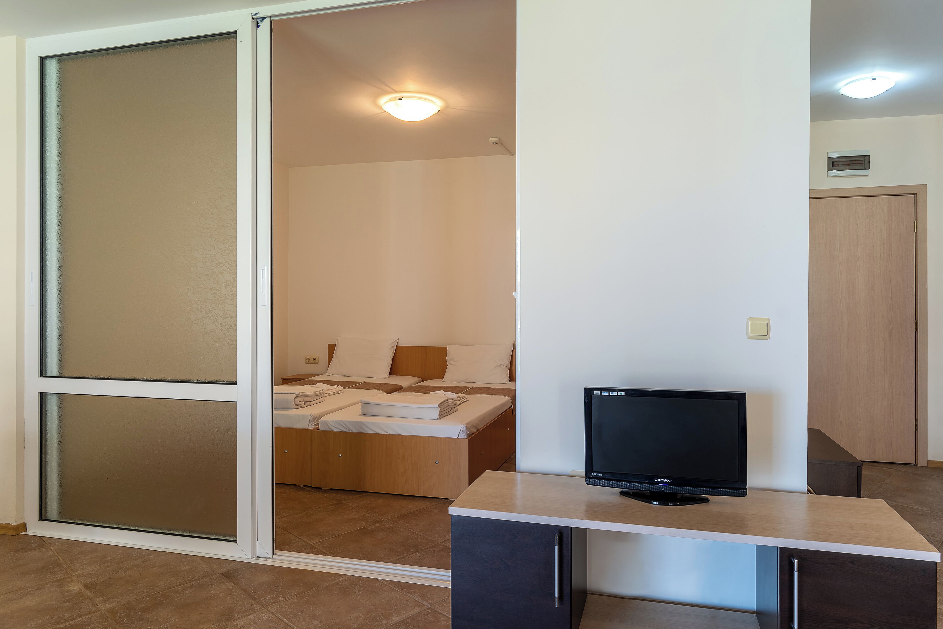 A room with a bed, a TV on a desk, and a sliding door.
