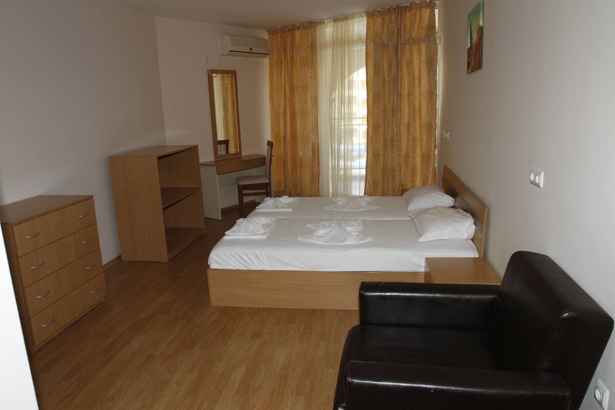 A bedroom with a bed, a desk, a chair, a dresser, and a black leather chair.