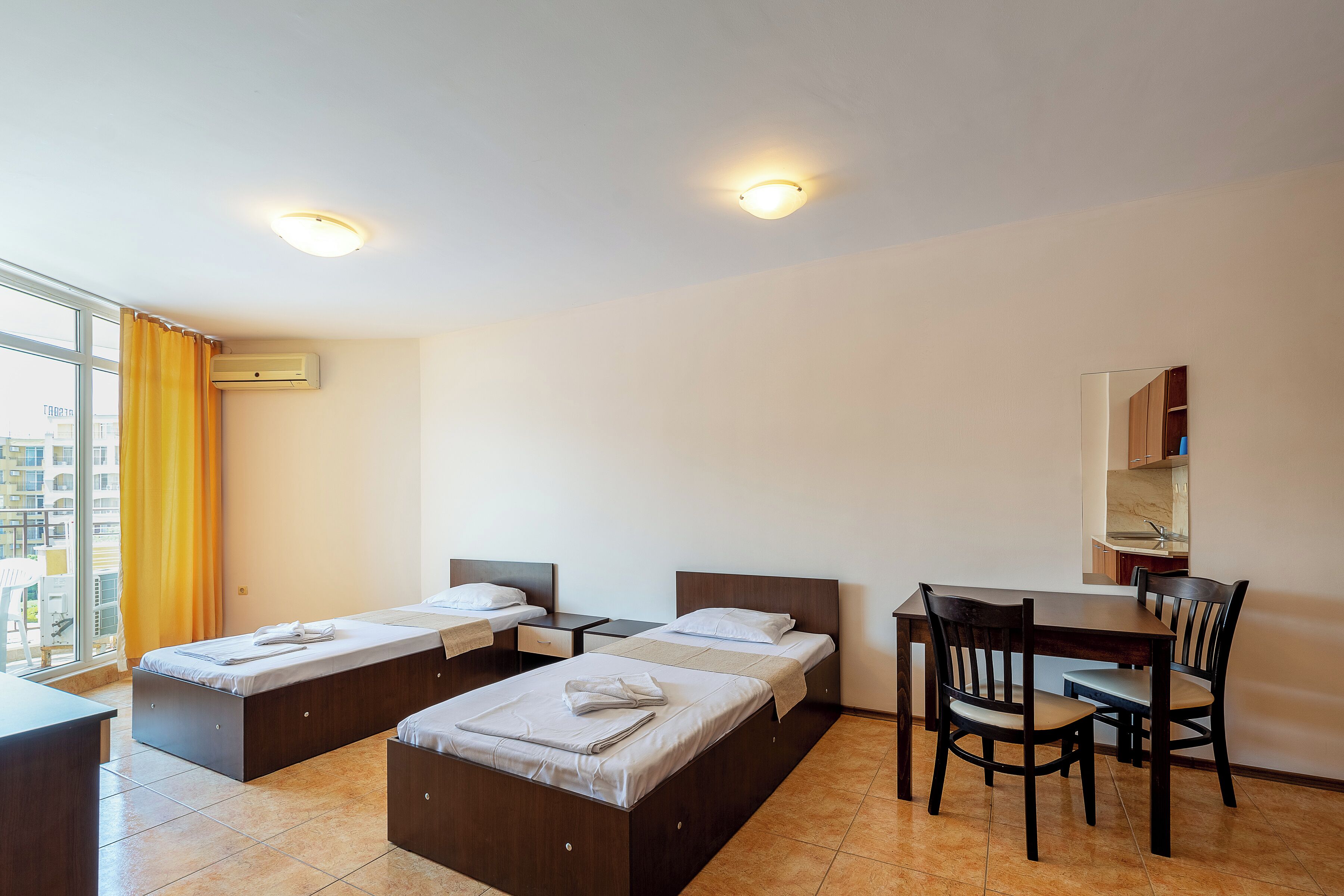 A hotel room with two beds, a desk, and a chair.