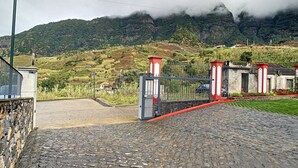 Ein gepflasterter Weg führt zu einem einkehrenden Eingang, vor dem sich eine Berglandschaft erhebt.