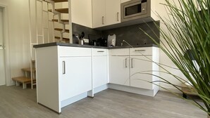 Una cocina moderna con armarios blancos, un microondas y una escalera de madera.