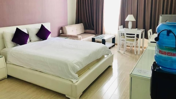 Hotelkamer met een bed, een bank, een kleine tafel, een stoel en een waterdispenser.