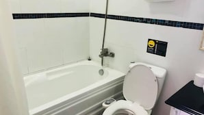 Een badkamer met een bad, toilet en een handdoekhouder.