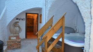 A spa area with a wooden staircase leading to a hot tub, a statue, and a door with a sign. - Santuari de Terrades (Terrades)