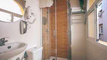 Een moderne badkamer met een douchecabine van glas, een wastafel, een toilet en een spiegel.
