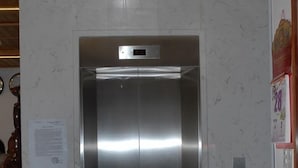 A modern elevator with a metallic finish, a control panel, and a digital display. - 7S Hotel Le Na (Cam Ly - Da Lat)