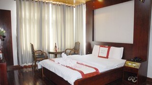 A hotel room with a wooden bed, two chairs, a small table, and a large window with curtains. - 7S Hotel Le Na (Cam Ly - Da Lat)