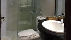 A modern bathroom with a glass-enclosed shower, a white toilet, a black sink, and a large mirror. - 7S Hotel Le Na (Cam Ly - Da Lat)