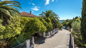 A residential street lined with palm trees and a house with a red roof. - Holiday Home Ore-Beach (Orebic)