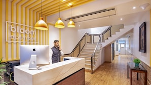 A reception desk with a computer, a sign reading "bloom BOUTIQUE", and a staircase leading to upper floors. - Bloom Boutique Gk-1 (New Delhi)