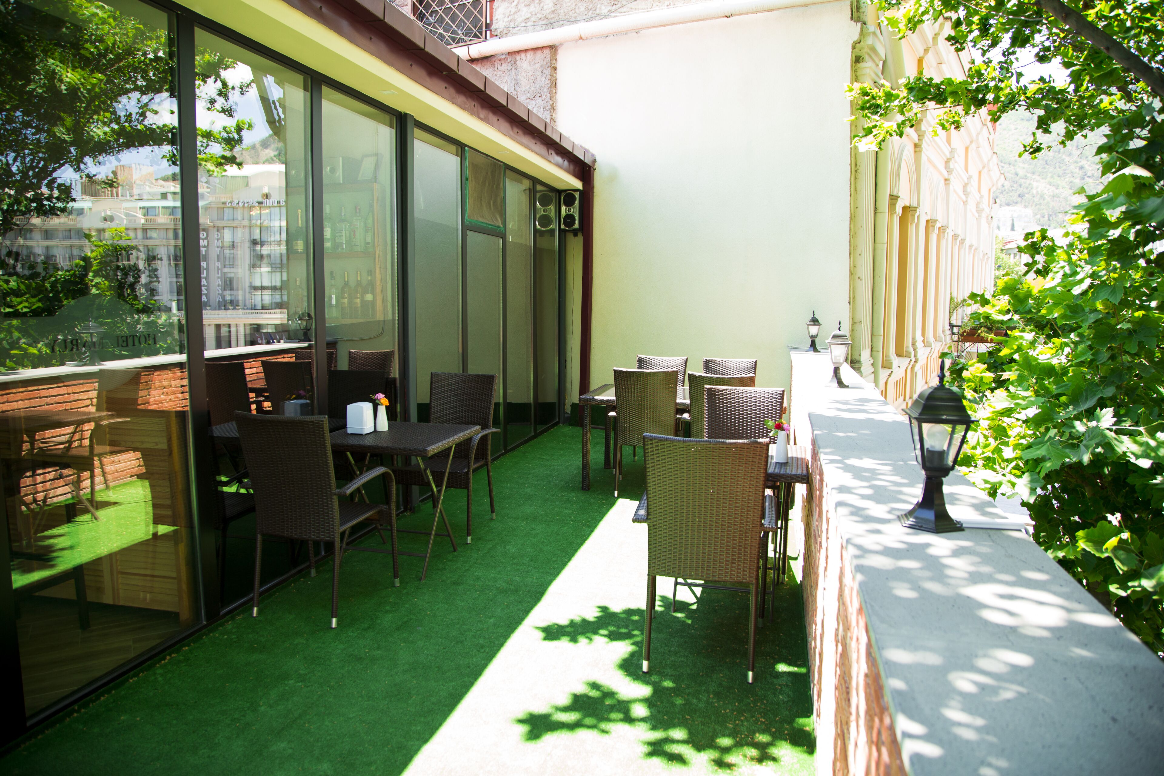 A patio area with outdoor seating, a green artificial turf, and a view of the city through large windows.