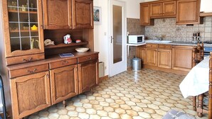 A kitchen with wooden cabinets, a microwave, and a tiled floor. - Port-Vendres: T2 with terrace and parking (Port-Vendres)