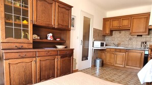 A kitchen with wooden cabinets, a microwave, and a trash can. - Port-Vendres: T2 with terrace and parking (Port-Vendres)
