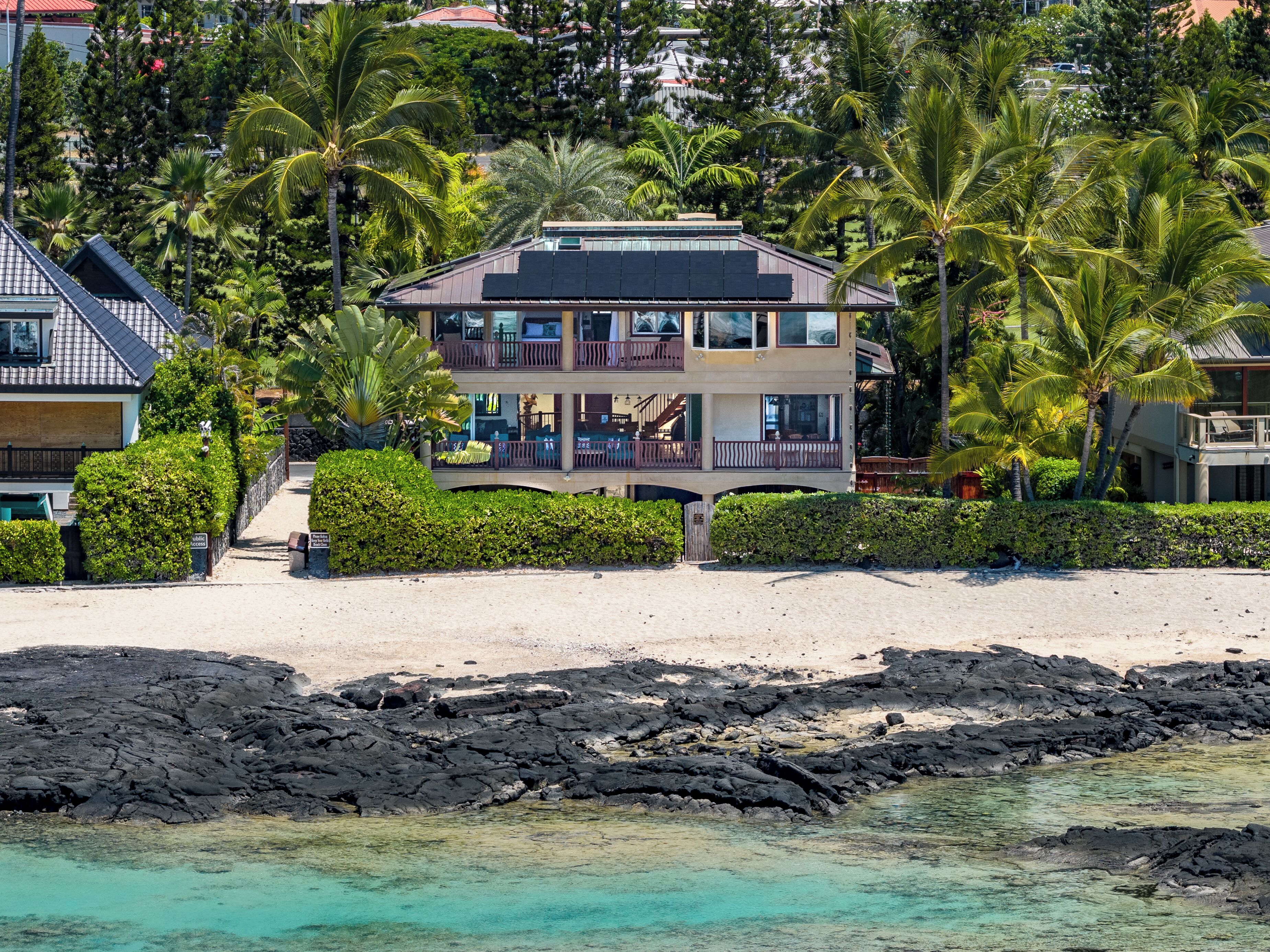 Une propriété située en bord de mer, comprenant un bâtiment à deux étages, un balcon et une vue sur l’océan.