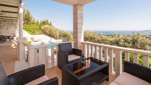 Un balcón con mobiliario de mimbre, una piscina y vistas al mar.
