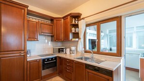 Una cocina con armarios de madera, microondas, cafetera y lavavajillas.