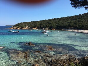 A coastal area with clear turquoise water, boats, and a rocky shoreline.