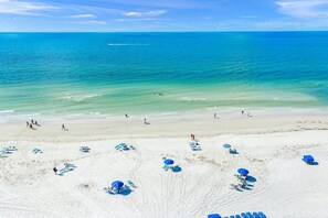 A beach with clear turquoise water, a few people, and several blue umbrellas and lounge chairs. - Stylish Siesta Key Canal Home w/ Private Pool & Boat Dock - Pet Friendly (Siesta Key)