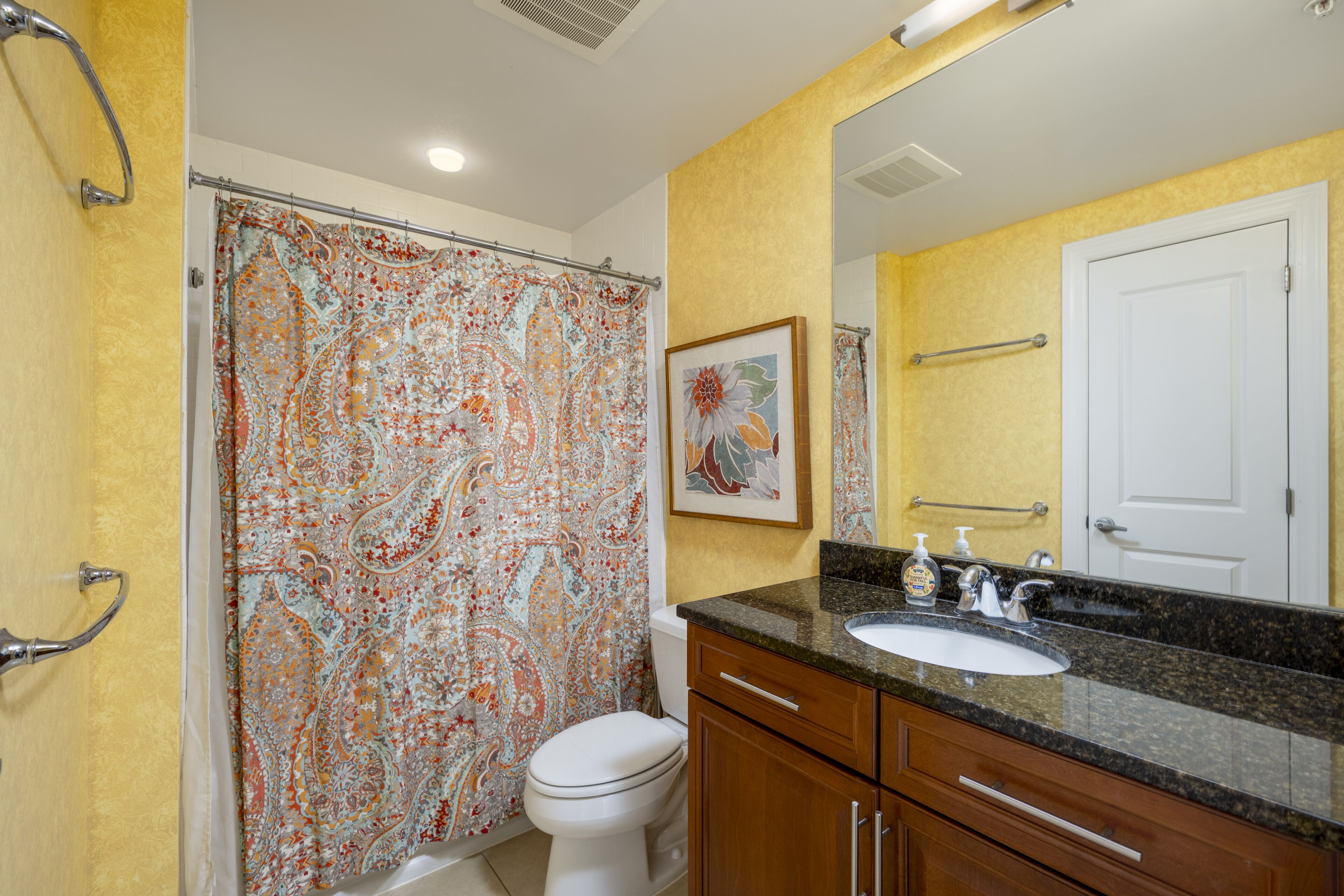 Une salle de bain avec un rideau de douche, des toilettes, un lavabo et des meubles en bois.
