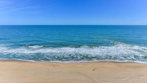 A beach with a clear view of the ocean, sandy shore, and a few people walking. - Gateway Grand 1206 Sleeps 12 and includes linens, George Foreman Grill and Game Table!! (Ocean City)