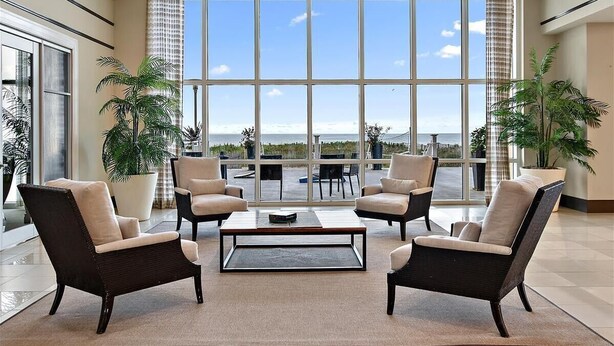 A spacious lobby with large windows offering a view of the ocean, featuring comfortable seating and potted plants. - Gateway Grand 1206 Sleeps 12 and includes linens, George Foreman Grill and Game Table!! (Ocean City)
