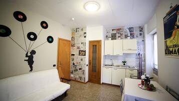 A compact living space with a kitchenette, a dining area, and a sofa.
