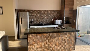 A modern kitchen with a central island, stainless steel appliances, and a mosaic backsplash. - FAMILY HOUSE-Olympia  (Olímpia)