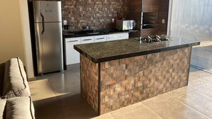 A modern kitchen with a central island, stainless steel appliances, and a patterned backsplash. - FAMILY HOUSE-Olympia  (Olímpia)