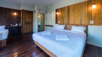 A hotel room with a large bed, wooden panel walls, a wooden floor, and a small desk with toiletries.