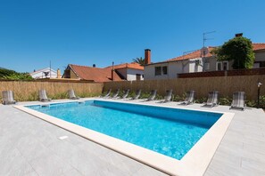 Piscine extérieure en saison, parasols, chaises longues