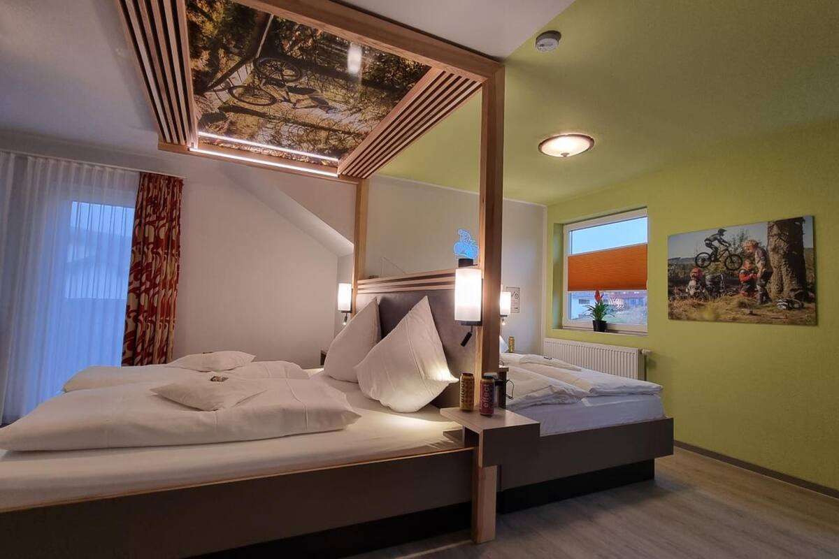 A modern hotel room with a large bed, a ceiling light fixture, and a window with a view of the outdoors.