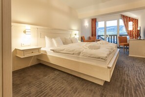Una cama grande con cabecera de madera, una mesita de noche y una silla cerca de una ventana con vistas.