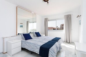 Un dormitorio con una cama grande, una mesita de noche, un espejo y una ventana con cortinas.
