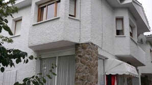 Ein Gebäude mit einer Steinsäule, weißen Außenwänden und mehreren Fenstern mit Fensterläden.