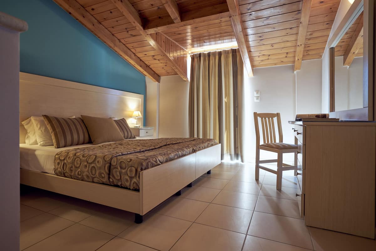 A bedroom with a bed, a desk, and a chair.